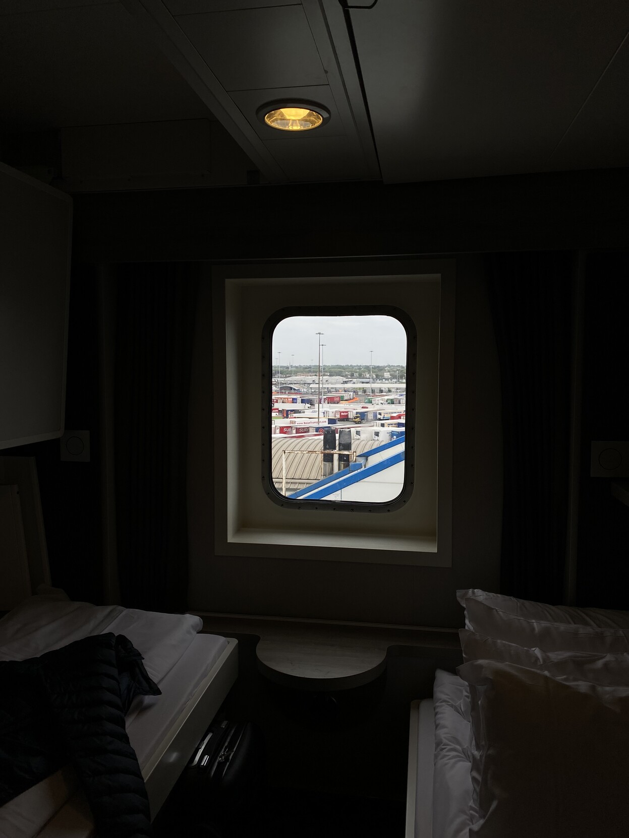 Dark ferry cabin interior with view out window to Dublin port scene containing truck trailers