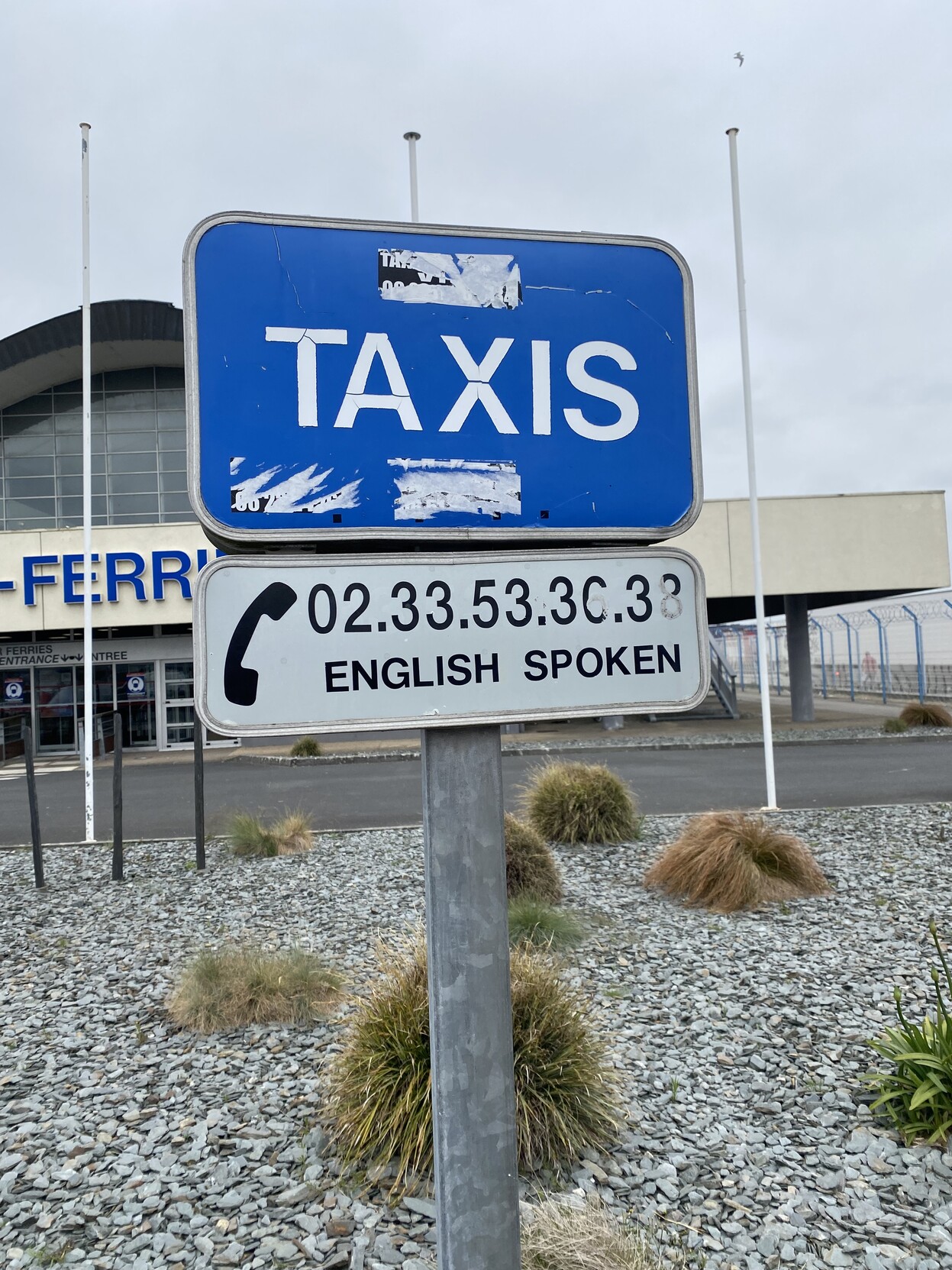 Taxi sign with a phone number in front of the ferry terminal building in Cherbourg 