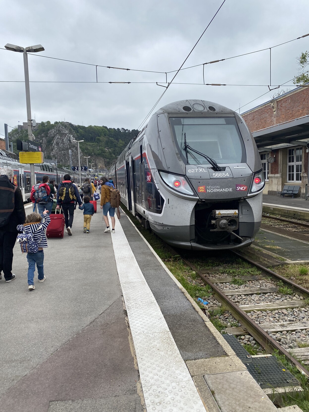 Modern double deck train viewed from the front at Gare de Cherbourg. Passengers walking along platform to board train.