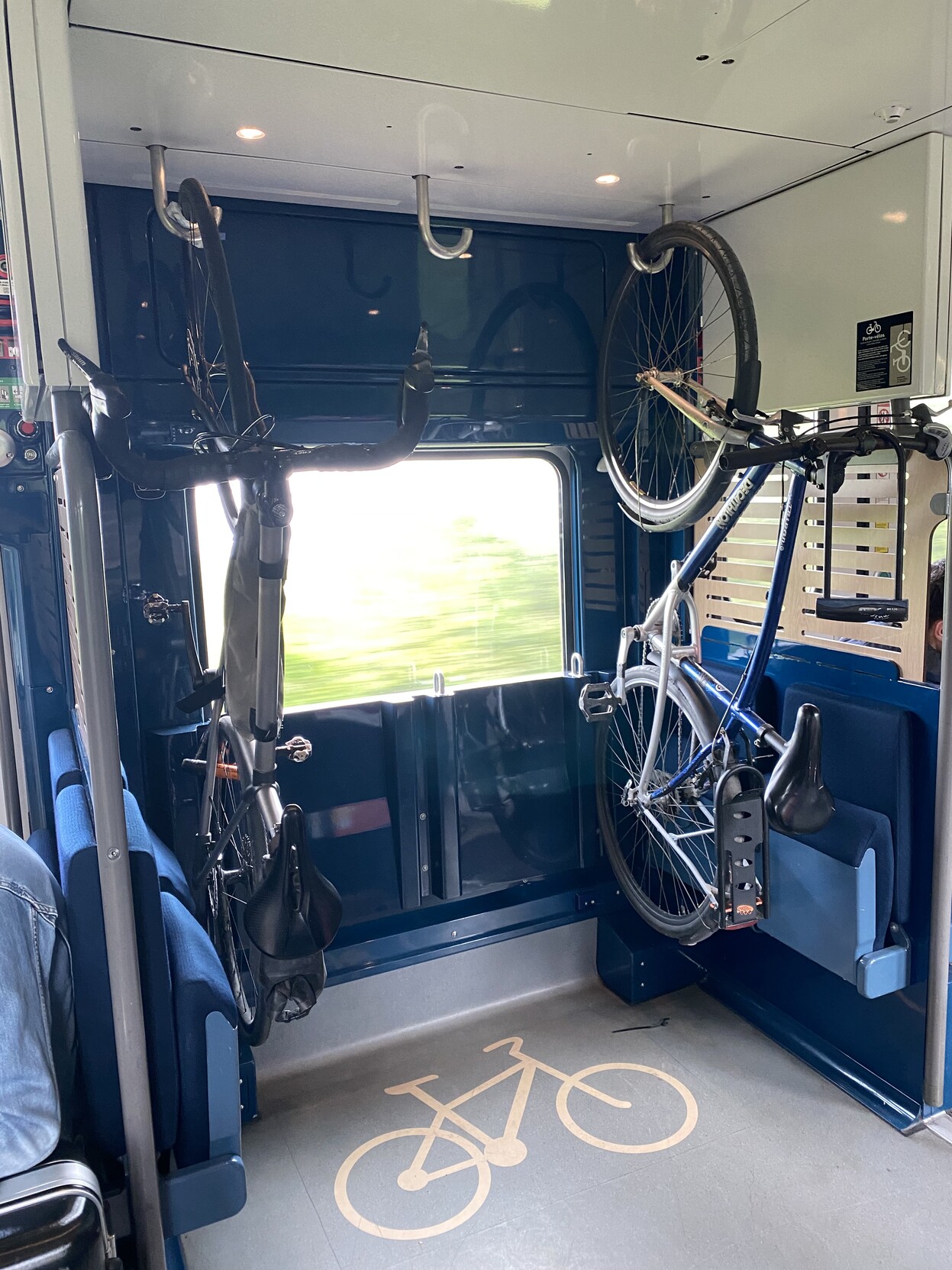 Bike racks on train. Two bikes hanging from hooks on ceiling and one hook free